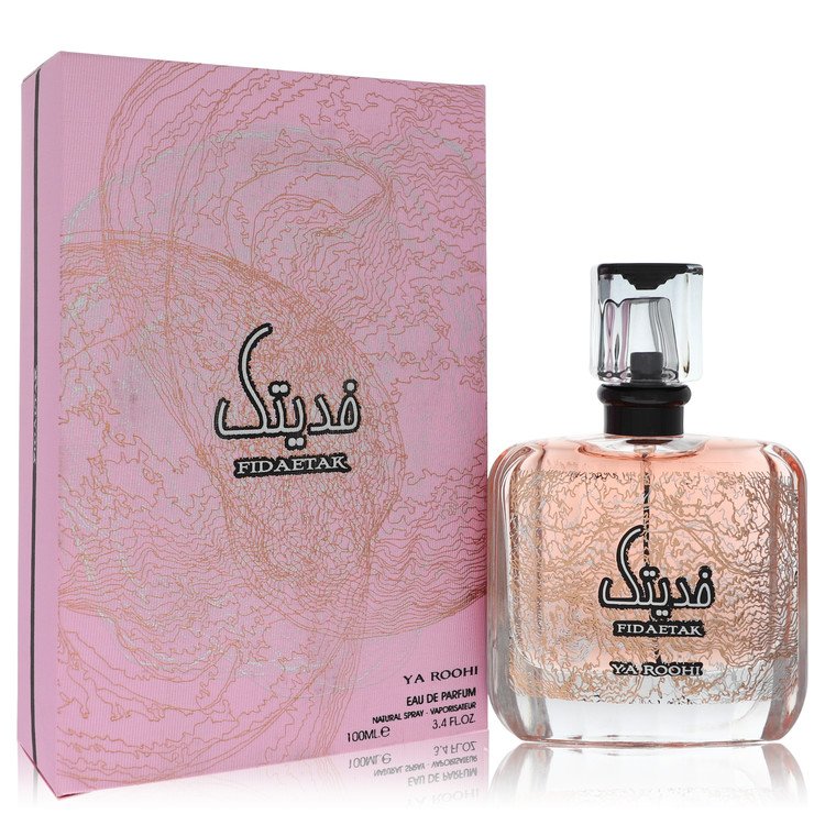 A clear glass bottle with gold accents and a black cap, labeled Al Zaafaran Fidaetak Ya Roohi, standing on a white surface by