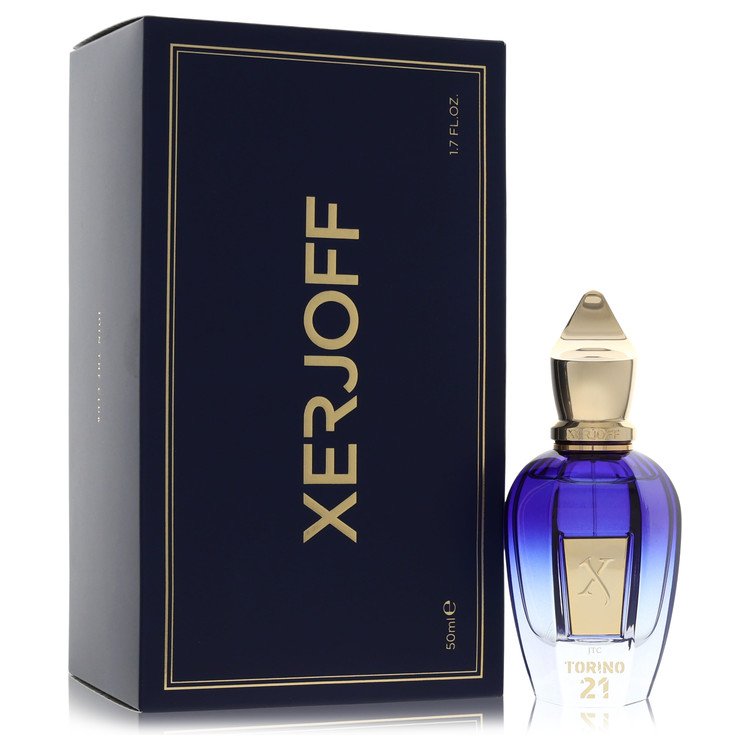 A clear glass bottle with gold accents and a black cap, labeled Xerjoff Torino 21, displayed on a wooden surface by The Fragr