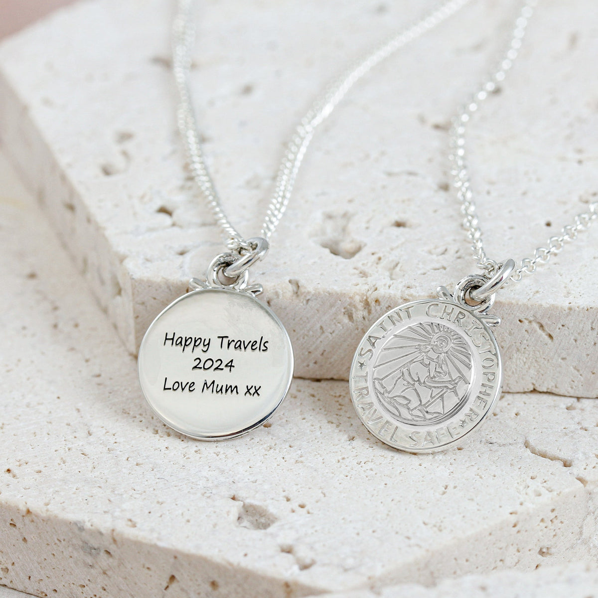 Silver St Christopher pendant on a chain with personalized engraving, styled on a wooden table.