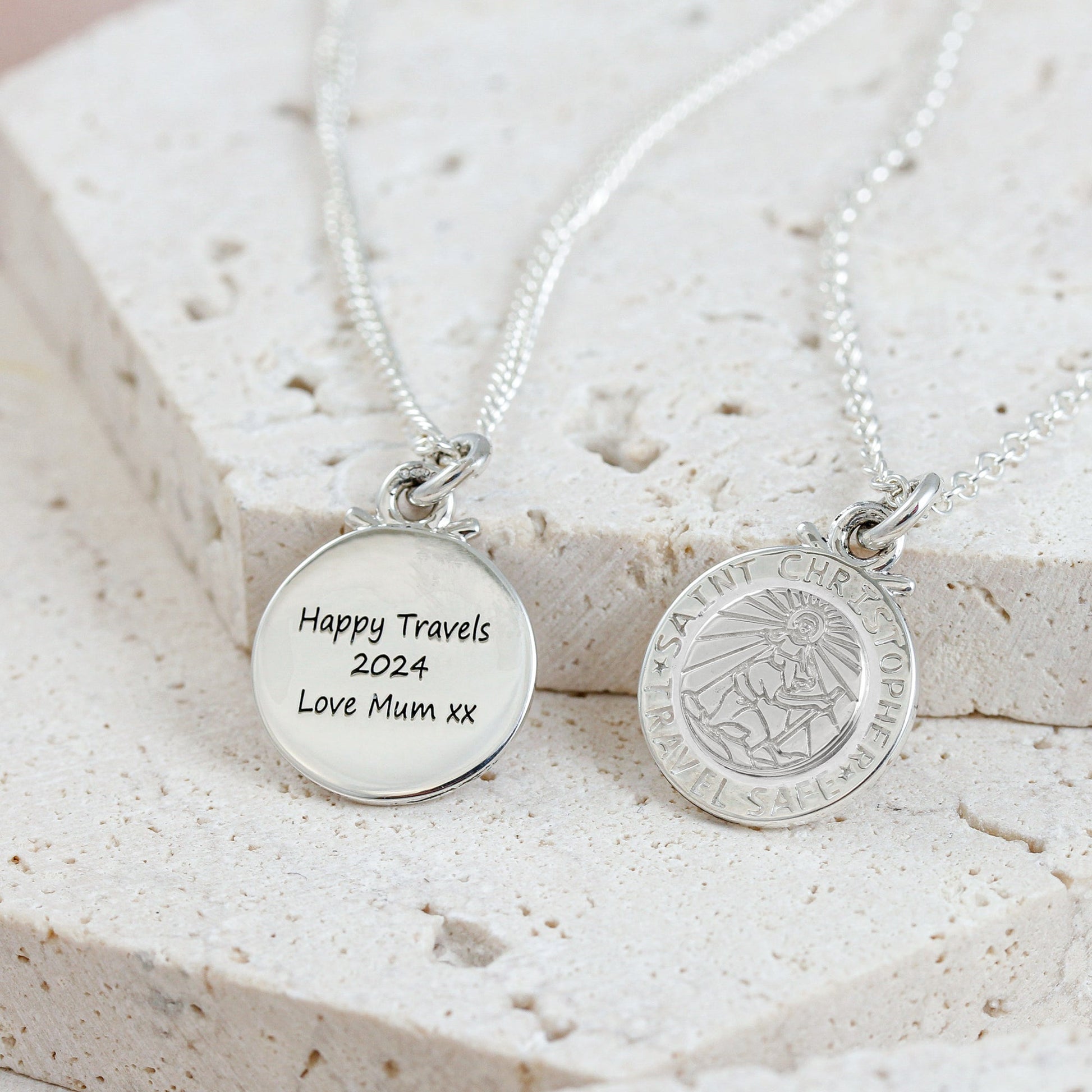 Silver St Christopher pendant on a chain with personalized engraving, styled on a wooden table.