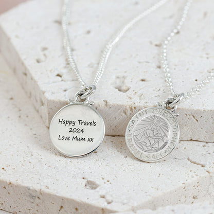 Silver St Christopher pendant on a chain with personalized engraving, styled on a wooden table.