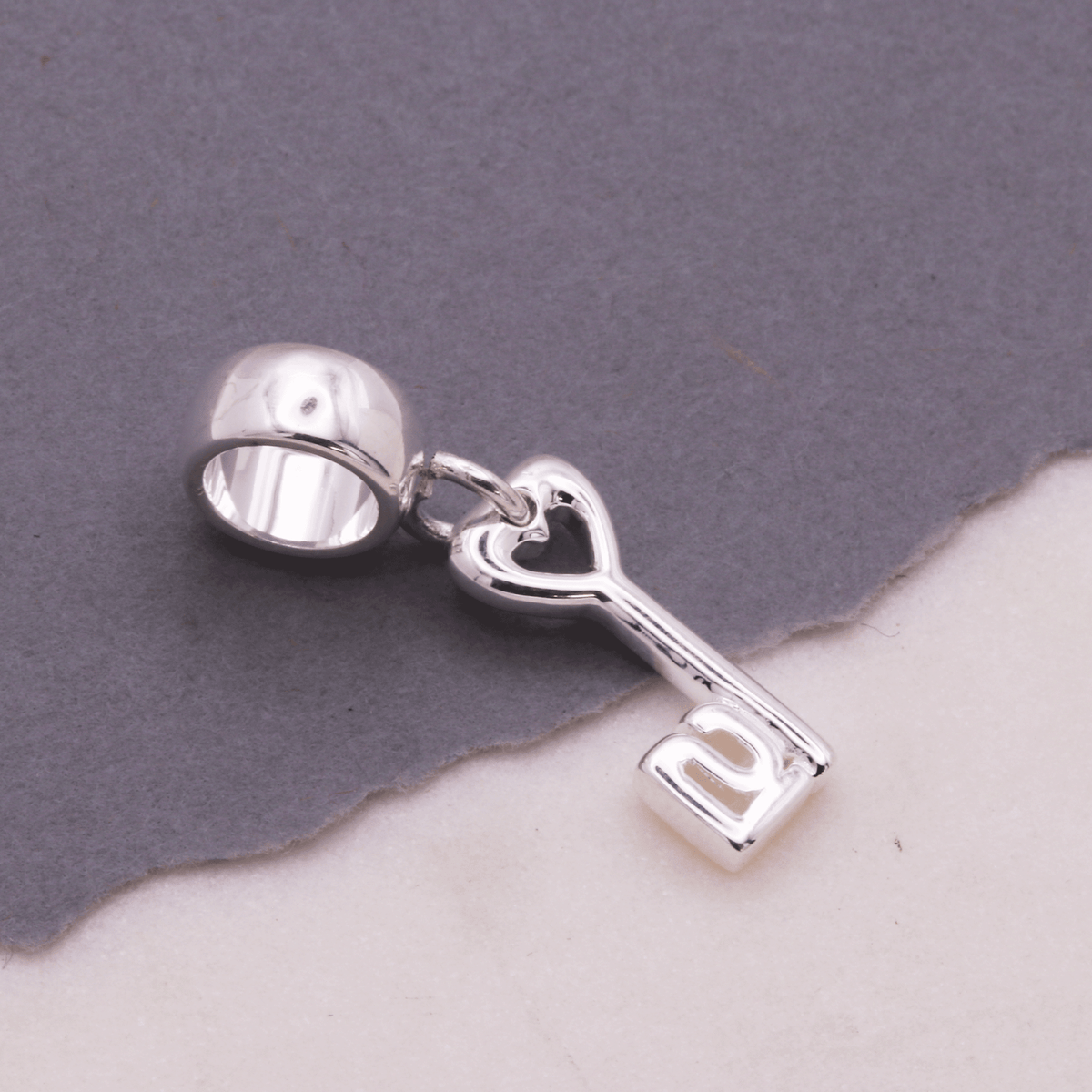 A silver 21st birthday charm with intricate detailing, displayed on a white background by Scarlett Jewellery.