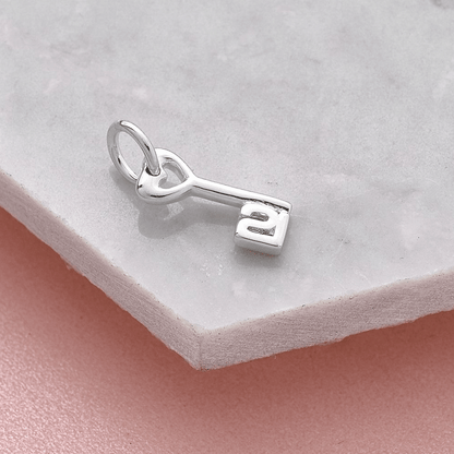 A silver 21st birthday charm with intricate detailing, displayed on a white background by Scarlett Jewellery.