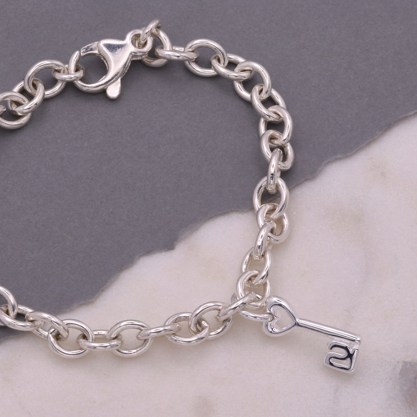 A silver 21st birthday charm displayed on a velvet background by Scarlett Jewellery.