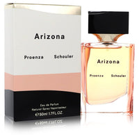 Blue glass bottle with gold accents resting on a white surface, labeled Proenza Schouler Arizona Eau de Parfum Spray for Wome