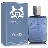 A clear glass bottle with gold accents and a black cap, labeled Sedley Eau De Parfum Spray by Parfums De Marly, standing on a