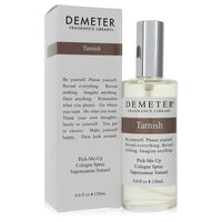 A clear glass bottle with a black cap and white label featuring the Demeter Tarnish Unisex Cologne Spray 4 oz by The Fragranc