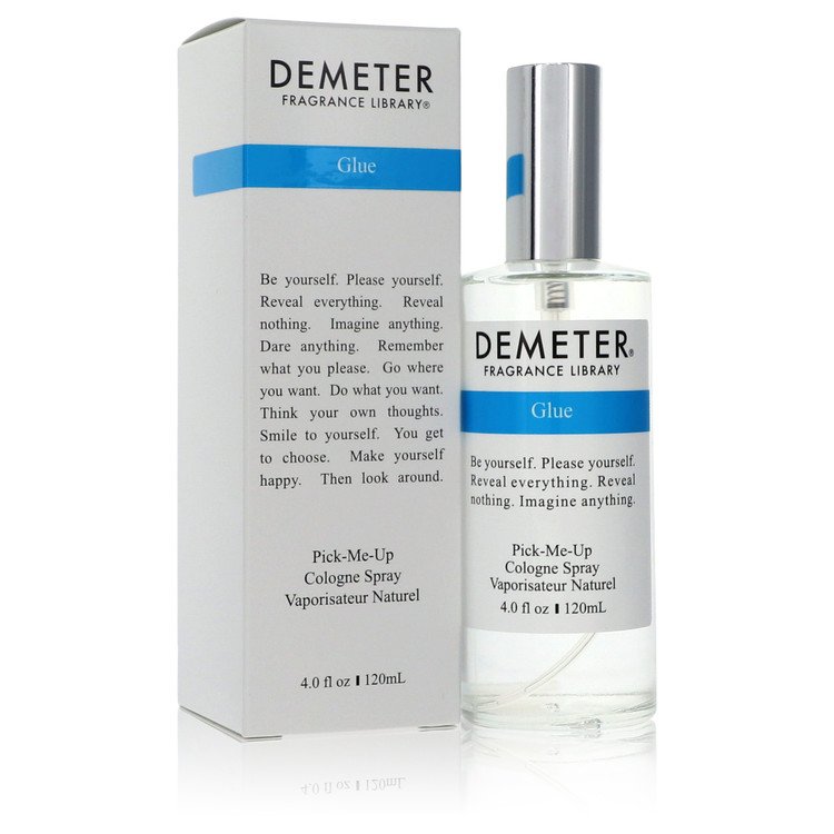 A clear glass bottle of Demeter Glue Cologne Spray with a white label and black text, standing on a wooden surface, by The Fr