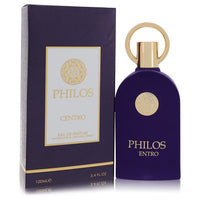A clear glass perfume bottle with a gold cap and minimalist label, standing on a white surface, labeled "Maison Alhambra Phil