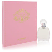 A clear glass bottle with gold accents and a black cap, labeled Mystique Musk Eau De Parfum, standing on a white surface by T