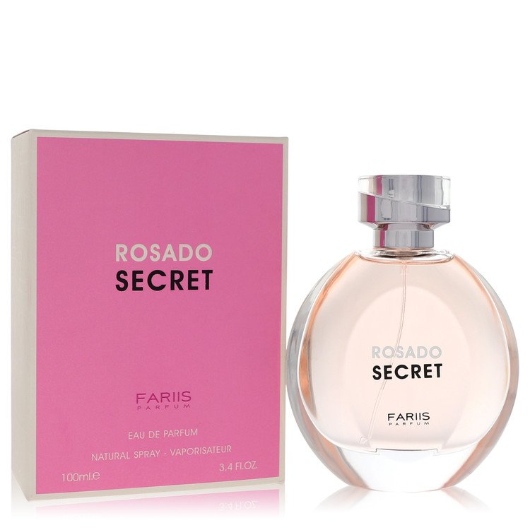 A clear glass perfume bottle with a pink cap and gold label, standing on a white surface, labeled Fariis Rosado Secret Eau De