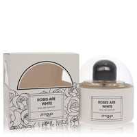 Afnan Zimaya Roses Are White eau de parfum spray in a white glass bottle with gold accents, standing on a wooden surface by T