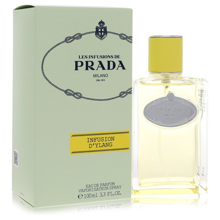 Prada Les Infusions Ylang Eau De Parfum Spray 3.3 oz in sleek white bottle with gold cap on wooden table by The Fragrance Ave