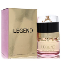 A golden bottle of Elvis Presley Legend Eau de Parfum Spray with a black label and white text, standing on a wooden surface b