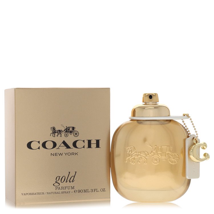 A gold perfume bottle with a sleek design and white label, standing on a wooden surface, labeled Coach Gold Eau De Parfum Spr
