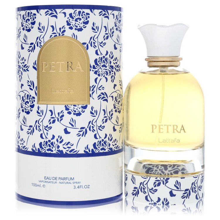 A clear glass bottle with a gold cap and black label, labeled "Petra" in bold white text, standing on a wooden surface by The