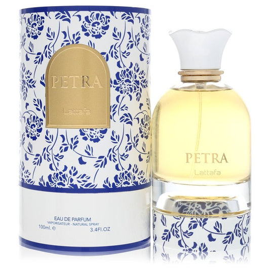 A clear glass bottle with a gold cap and black label, labeled "Petra" in bold white text, standing on a wooden surface by The