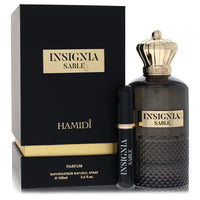 Blue glass perfume bottle with gold label and black cap, standing on a wooden surface, labeled Hamidi Insignia Sable for Men 