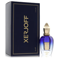 A clear glass bottle with gold accents and a black cap, labeled Xerjoff Torino 21, displayed on a wooden surface by The Fragr