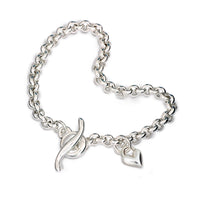 A silver heart chain charm bracelet with a detailed belcher design, featuring a central heart pendant, by Scarlett Jewellery.