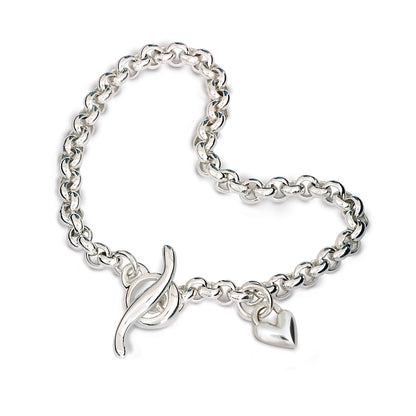 A silver heart chain charm bracelet with a detailed belcher design, featuring a central heart pendant, by Scarlett Jewellery.