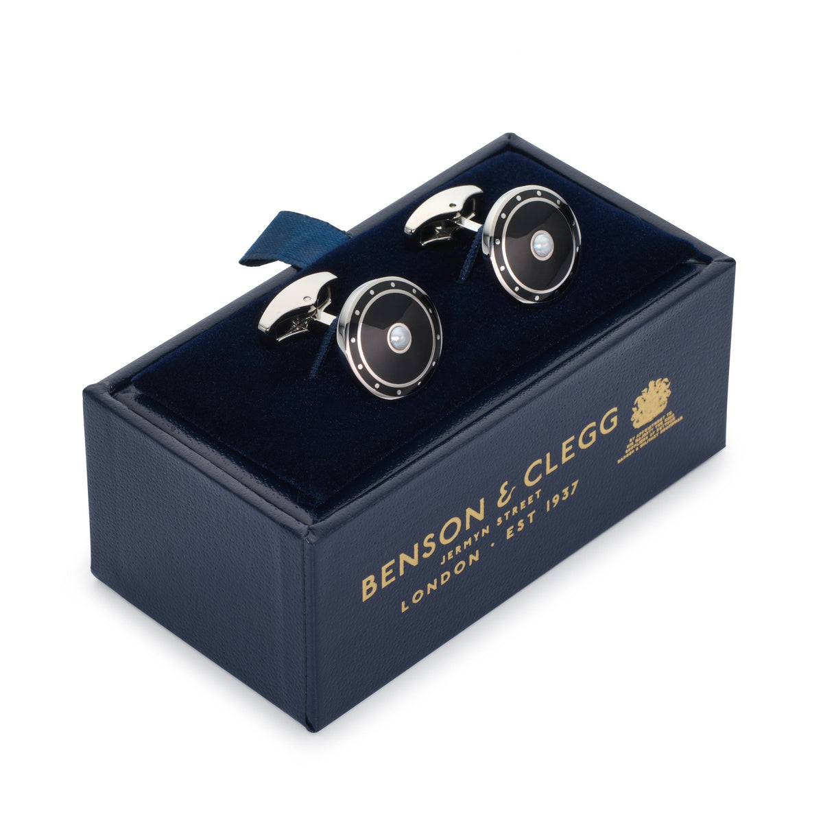 Black onyx cufflinks with polished silver accents, styled on a dark fabric background, by Benson & Clegg.