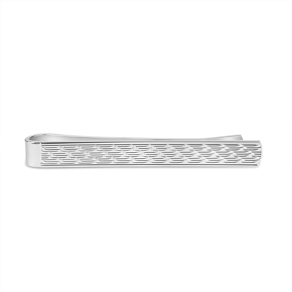 A silver tie slide featuring a fox head pattern with intricate detailing, displayed on a dark background.