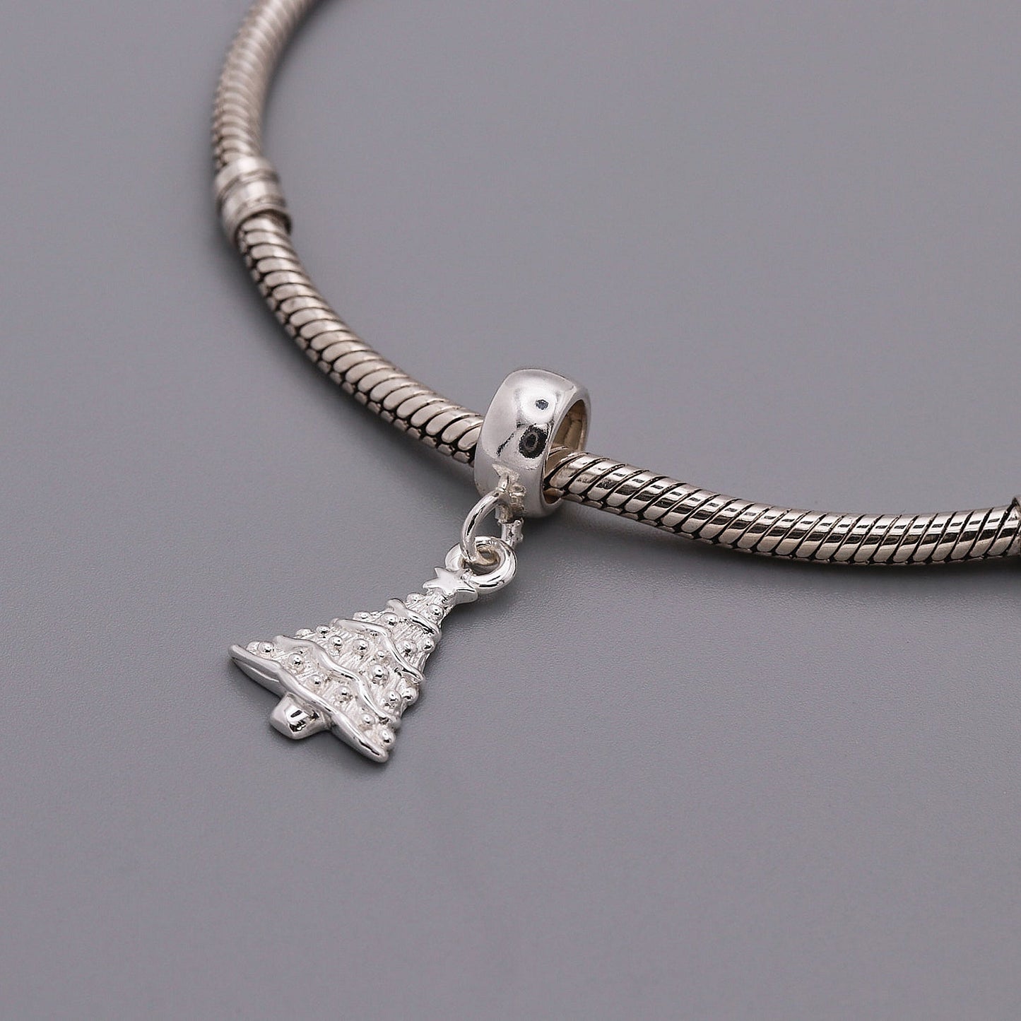 A silver Christmas tree charm with personalized engraving, displayed on a white background, by Scarlett Jewellery.