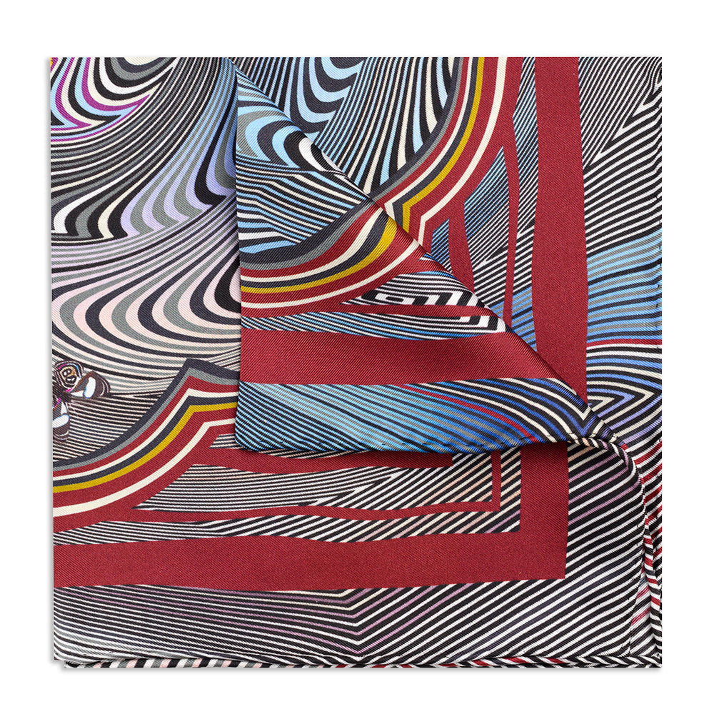 A cobalt blue zig zag pattern on a silk pocket square with white edges, displayed flat on a neutral background by Benson & Cl