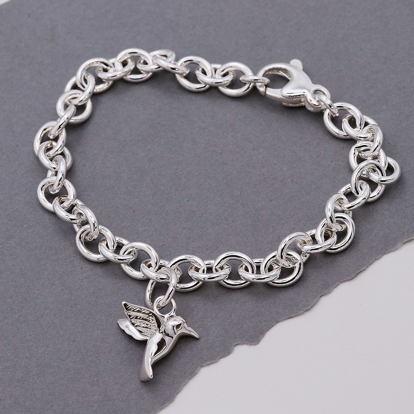 Silver hummingbird charm with delicate wings, styled on a jewelry display by Scarlett Jewellery.