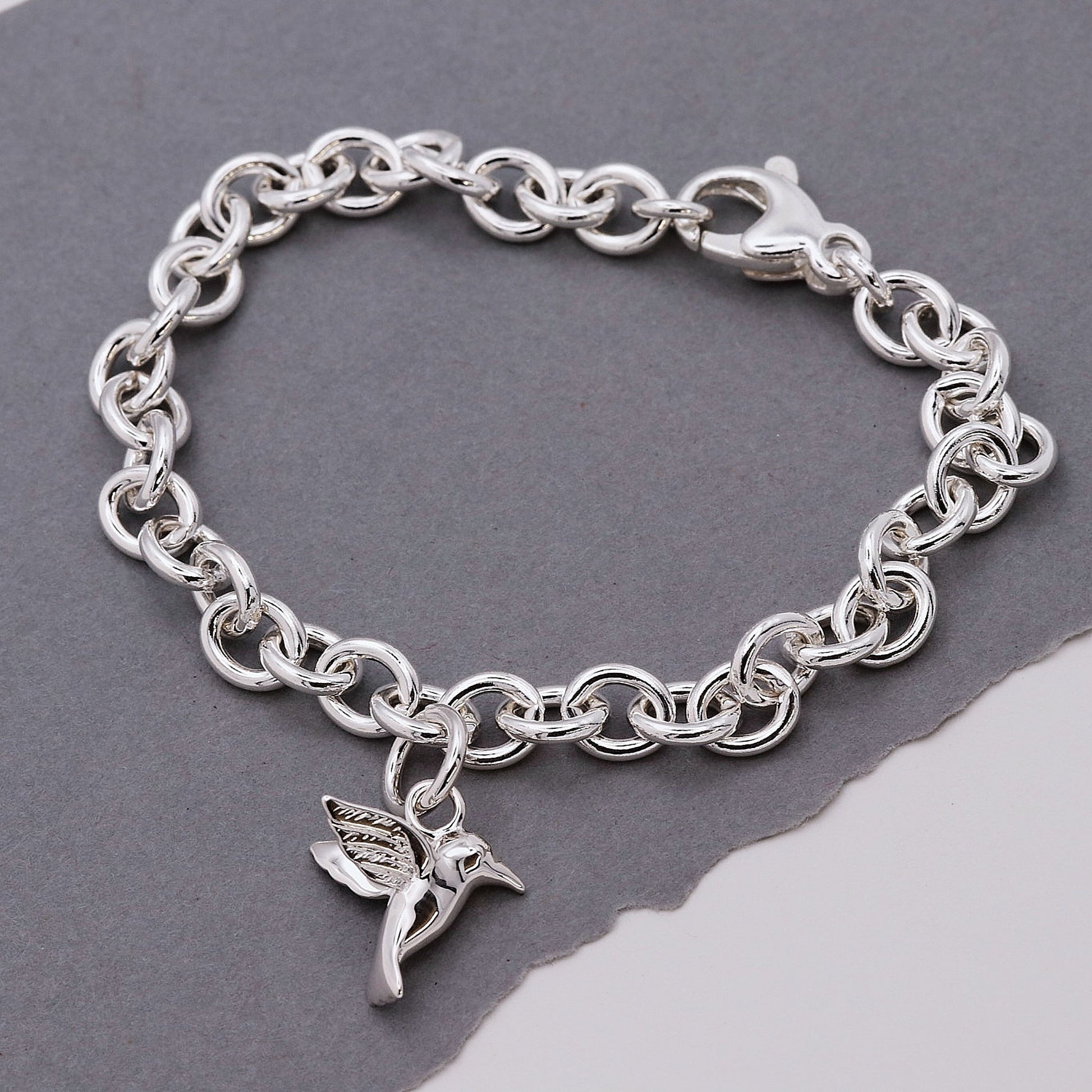 Silver hummingbird charm with delicate wings, styled on a jewelry display by Scarlett Jewellery.