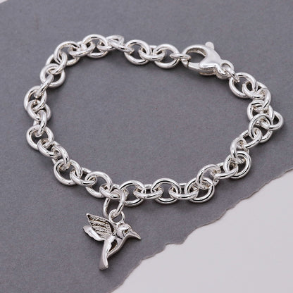 Silver hummingbird charm with delicate wings, styled on a jewelry display by Scarlett Jewellery.