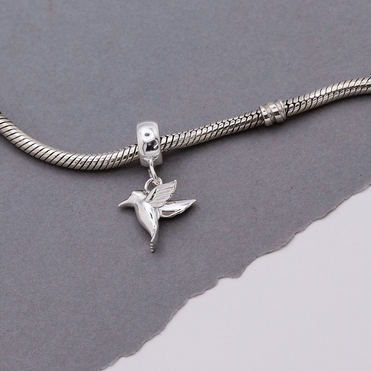 Silver hummingbird charm with delicate wings, styled on a chain, by Scarlett Jewellery.