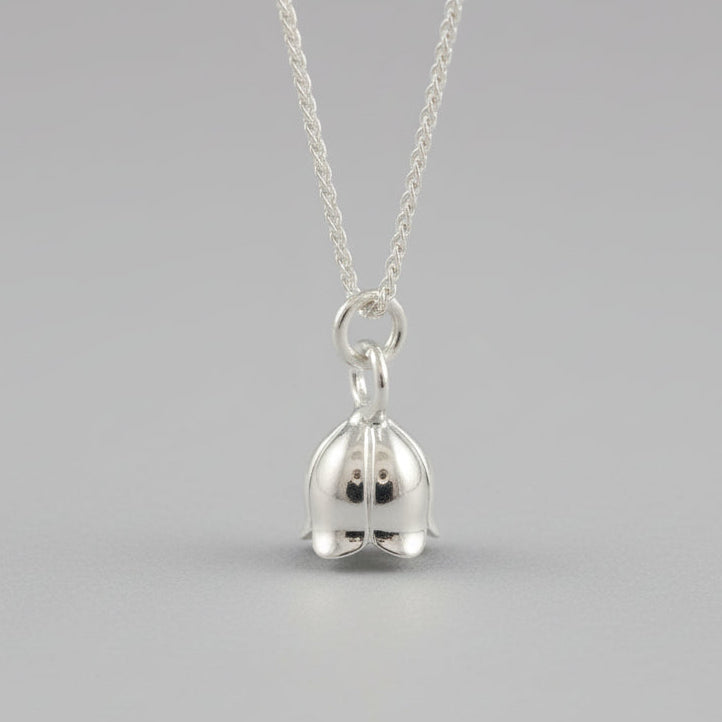 A silver lily of the valley flower charm with delicate detailing, shown at a slight angle, by Scarlett Jewellery.