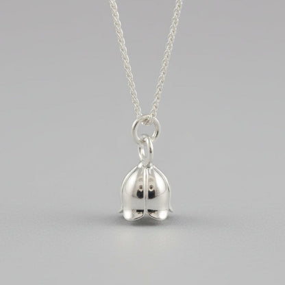 A silver lily of the valley flower charm with delicate detailing, shown at a slight angle, by Scarlett Jewellery.