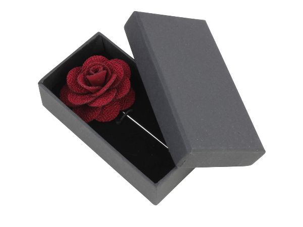 A burgundy silk boutonniere with delicate detailing, displayed on a white background by Benson & Clegg.