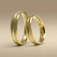 A gold wedding band with linear texture in 14ct gold, shown against a dark background, part of the Aurelia line by Majestic J