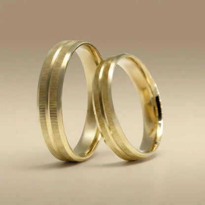 A gold wedding band with linear texture in 14ct gold, shown against a dark background, part of the Aurelia line by Majestic J