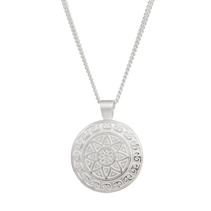 A silver mandala necklace with intricate Aztec design worn on a chain by Scarlett Jewellery.