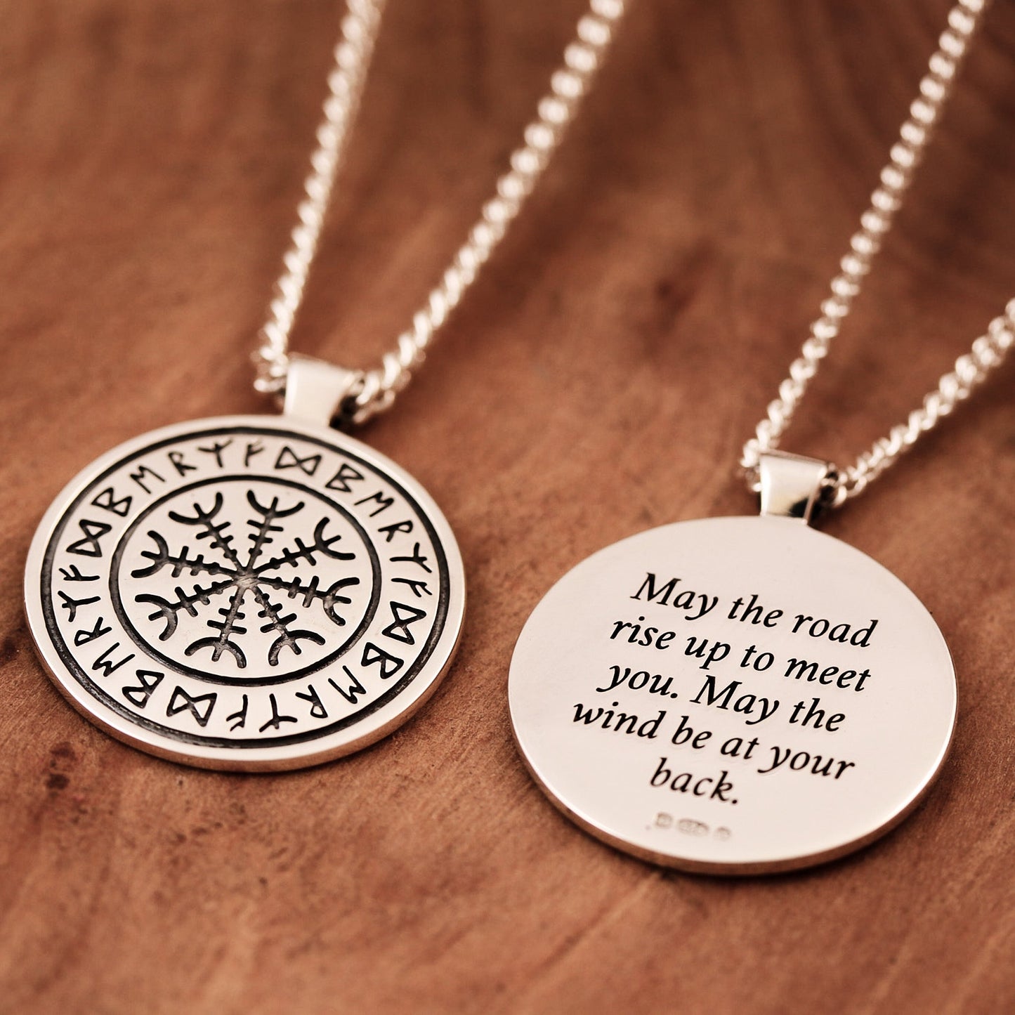 A silver Viking rune necklace with personalized engraving, displayed on a wooden background by Scarlett Jewellery.