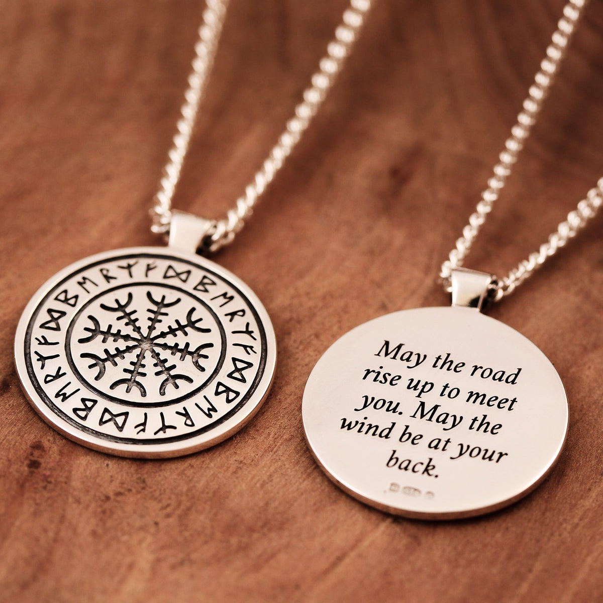 A silver Viking rune necklace with personalized engraving, displayed on a wooden background by Scarlett Jewellery.