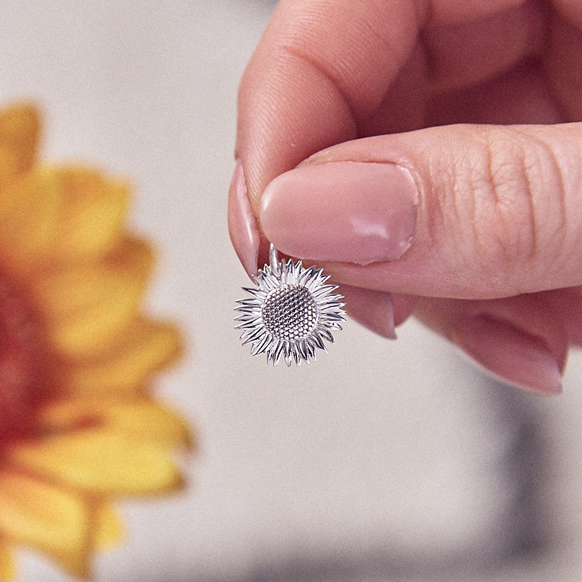 Sunflower silver charm with intricate details, styled on a necklace chain by Scarlett Jewellery.