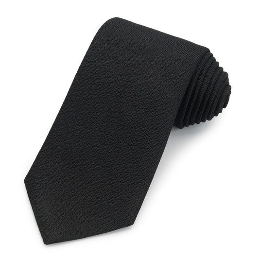 Black three-fold silk tie in non-crease weave displayed on a wooden table by Benson & Clegg.