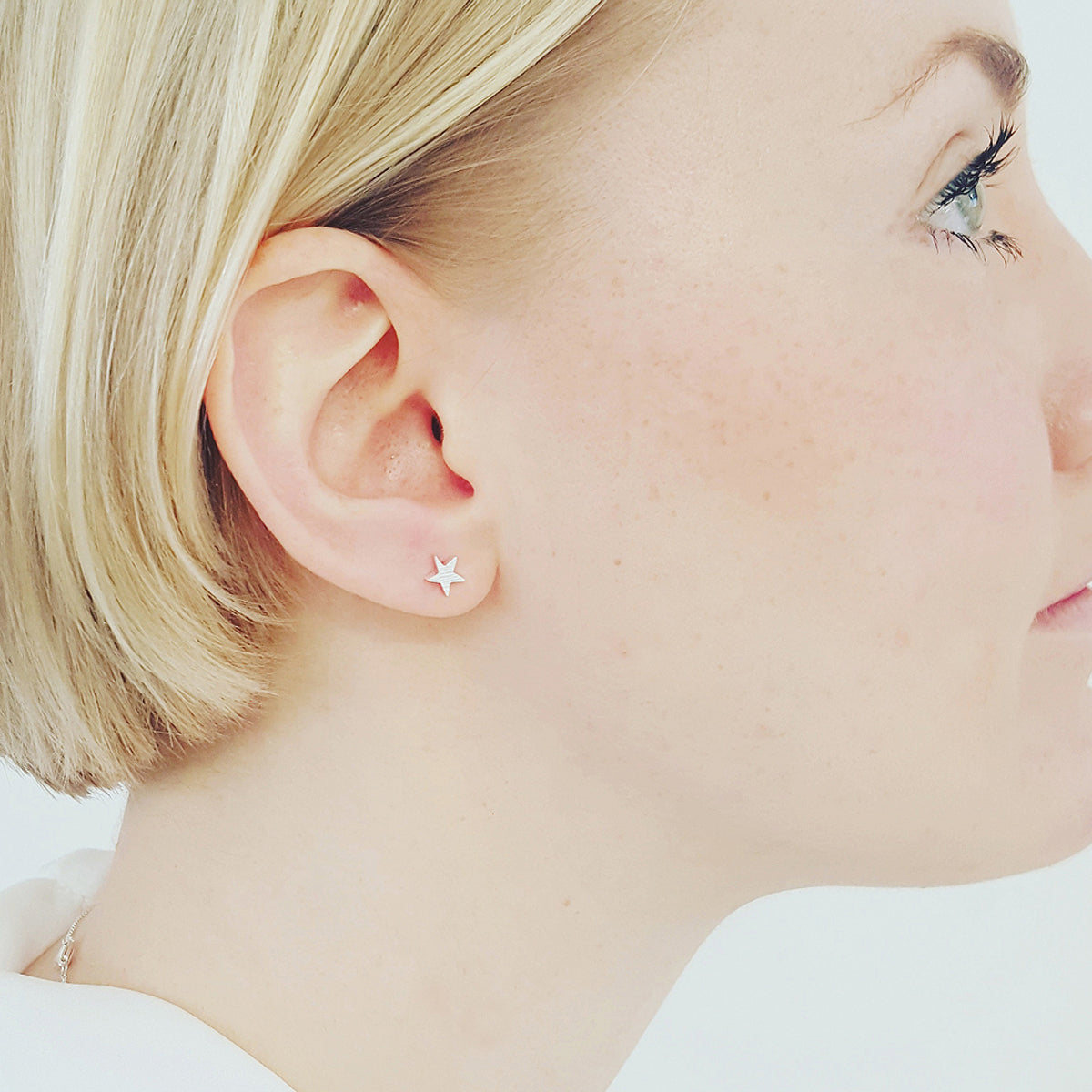Silver stud earrings with a star-shaped design, featuring a twilight blue accent, by Scarlett Jewellery.