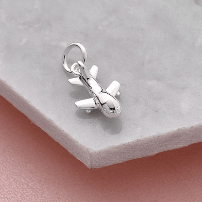 Aeroplane silver charm with intricate detailing, displayed on a soft pink background by Scarlett Jewellery.
