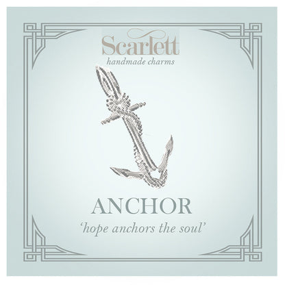 A silver anchor charm with intricate detailing, displayed on a soft white background, by Scarlett Jewellery.