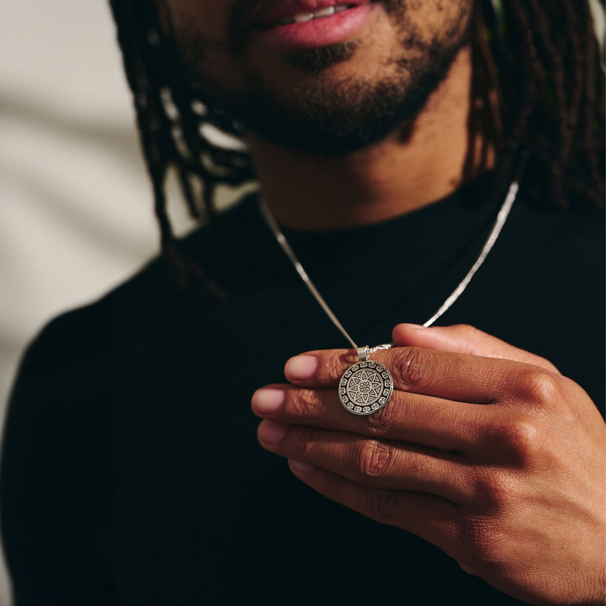 A silver mandala necklace with intricate Aztec design worn around the neck by Scarlett Jewellery
