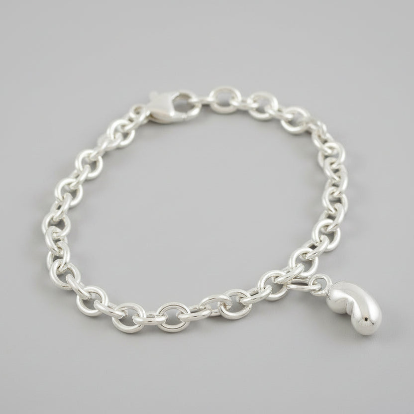 Silver baby bean charm with delicate detailing, displayed on a white background by Scarlett Jewellery.