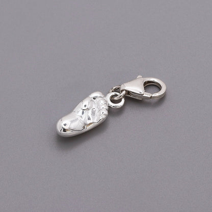 A silver baby charm with personalized engraving, displayed on a soft pink background, by Scarlett Jewellery.