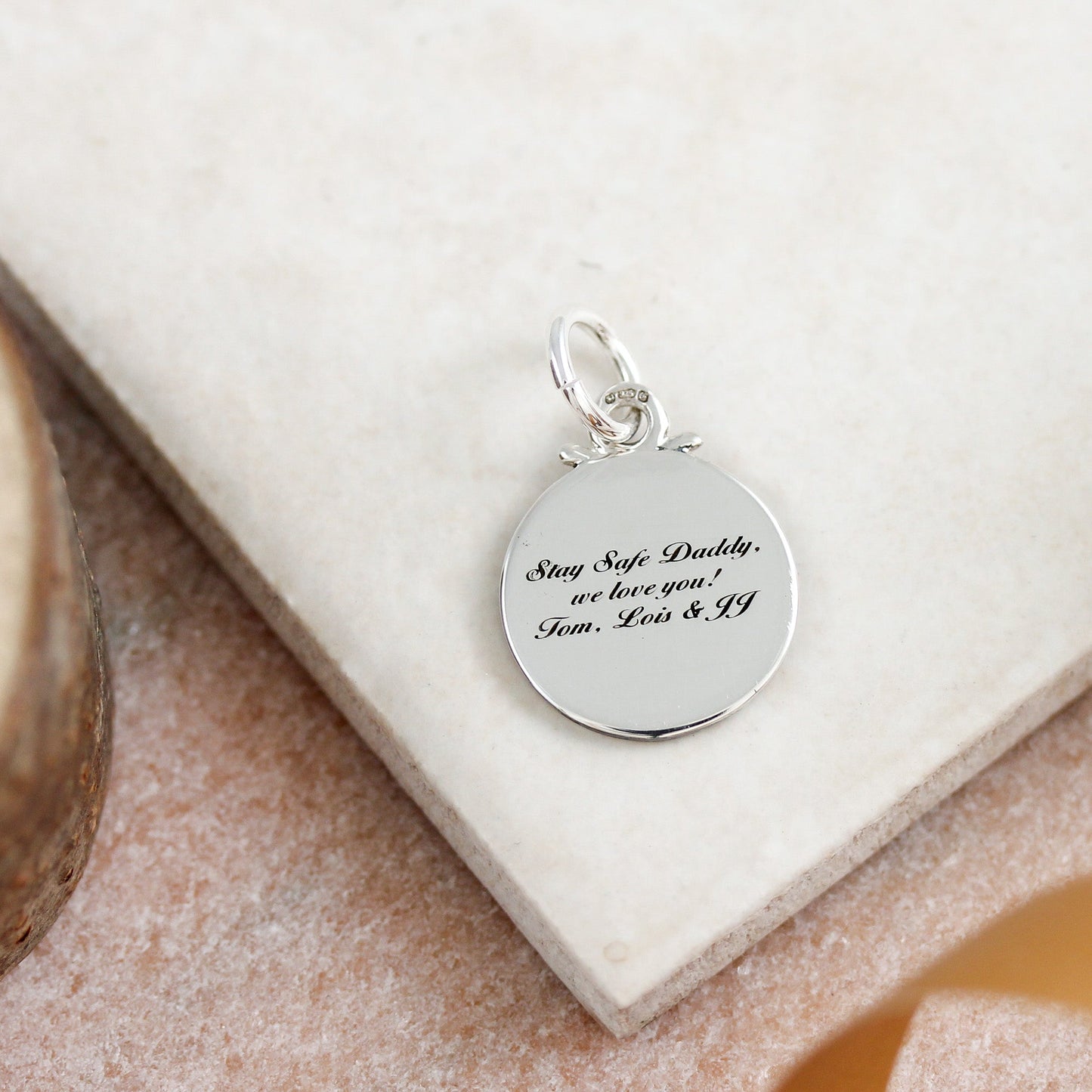Silver compass charm with personalized engraving, styled on a jewelry display by Scarlett Jewellery.